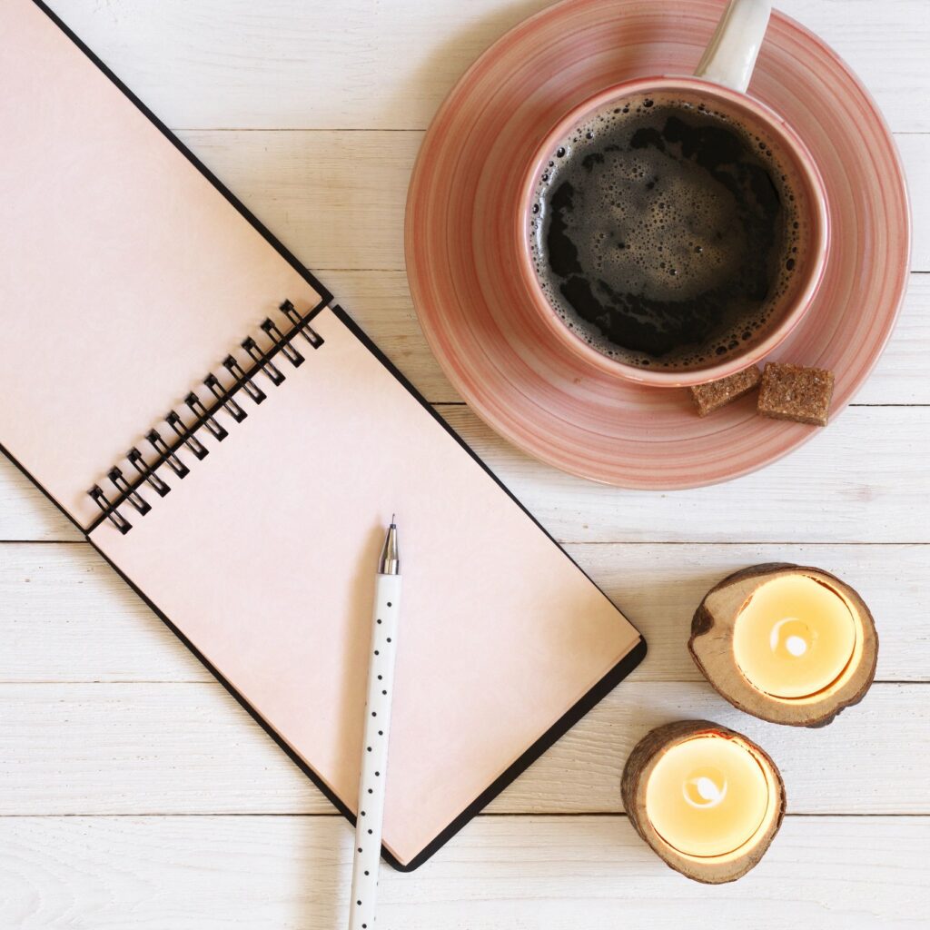 Notepad with pen, coffee and candles on desk